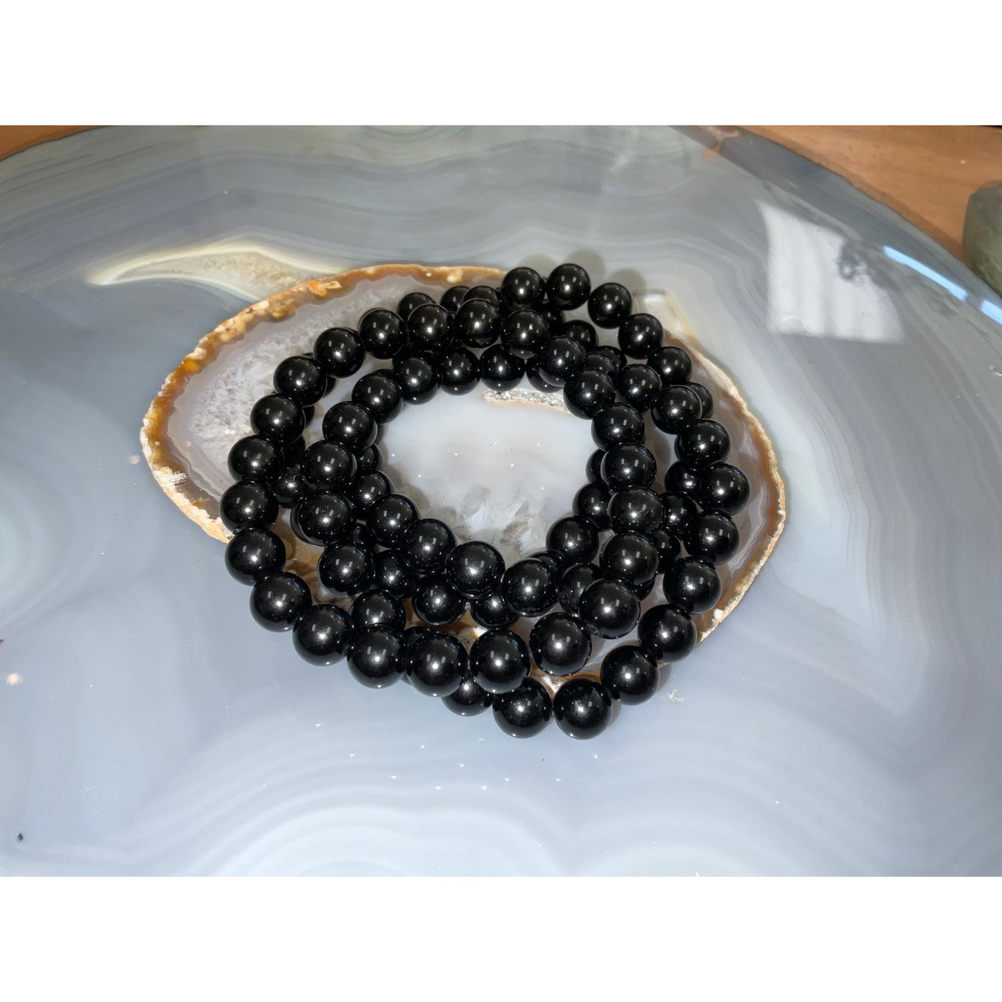 Black obsidian bracelet detail, matte black polished volcanic glass beads close-up
